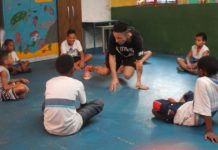professor de dança ensina movimento de break para crianças sentadas no chão