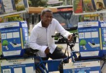 ex-cobrador de ônibus ao lado de bicicleta transformada em biblioteca