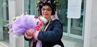 jovem com síndrome de down segura buquê de flores em frente a prédio de universidade